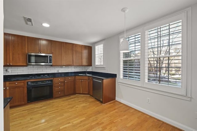 kitchen featuring black appliances, visible vents, brown cabinetry, and decorative backsplash