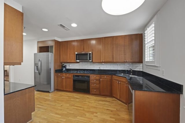 kitchen featuring tasteful backsplash, visible vents, appliances with stainless steel finishes, light wood-type flooring, and a sink