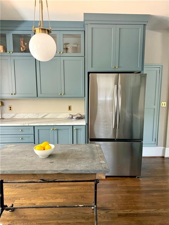 kitchen with dark wood-type flooring, pendant lighting, blue cabinets, and stainless steel refrigerator