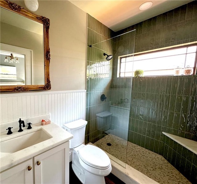 bathroom featuring toilet, a tile shower, and vanity