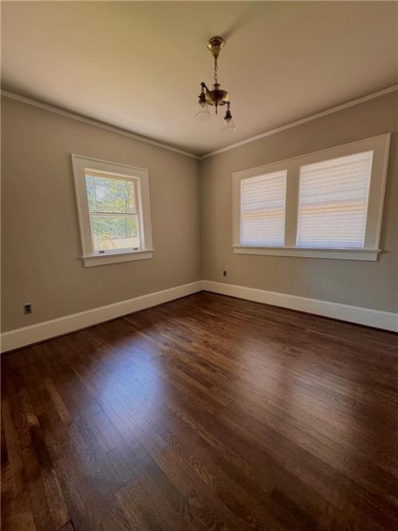 spare room with crown molding, an inviting chandelier, and dark hardwood / wood-style flooring