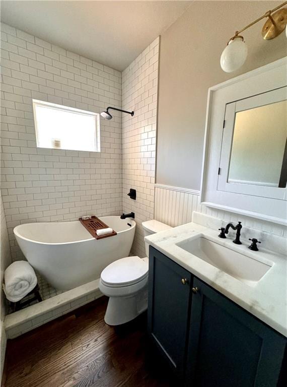 bathroom with a bath, hardwood / wood-style floors, toilet, and vanity