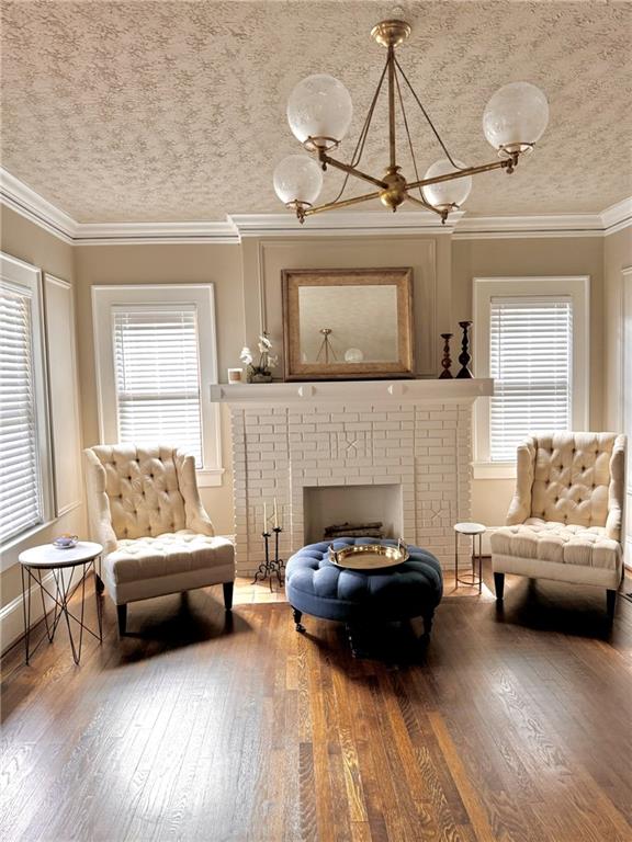 living area with a wealth of natural light, hardwood / wood-style flooring, and a brick fireplace