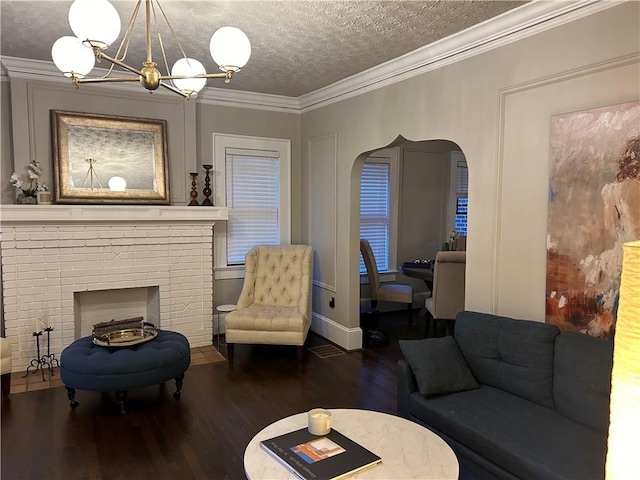 living room with a fireplace, a notable chandelier, ornamental molding, a textured ceiling, and dark hardwood / wood-style flooring