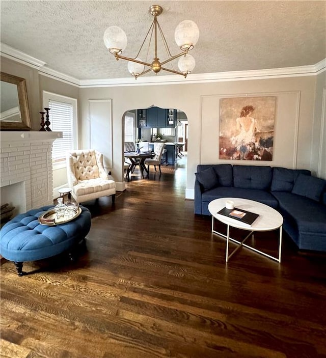 living room with crown molding, dark wood-type flooring, a textured ceiling, and a chandelier