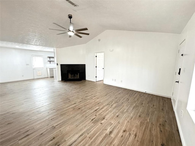 unfurnished living room featuring ceiling fan, lofted ceiling, a fireplace, wood finished floors, and a textured ceiling