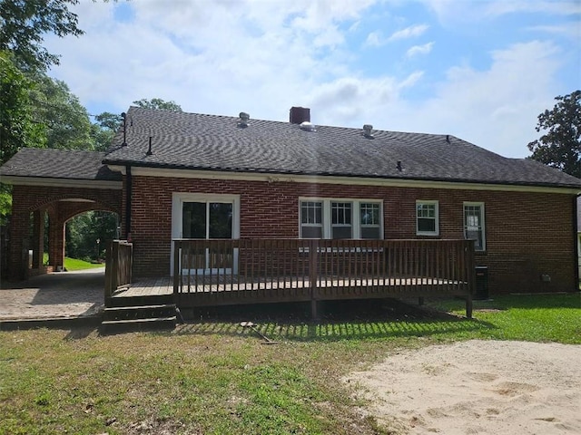 rear view of property featuring central air condition unit, a lawn, roof with shingles, a wooden deck, and brick siding