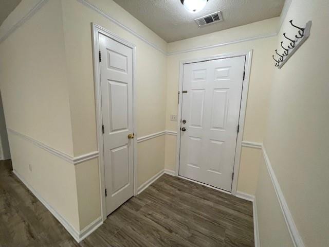 doorway to outside with a textured ceiling and dark hardwood / wood-style floors