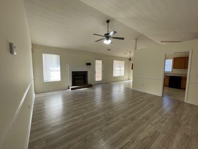 unfurnished living room featuring a fireplace with raised hearth, light wood-style flooring, a healthy amount of sunlight, and a ceiling fan