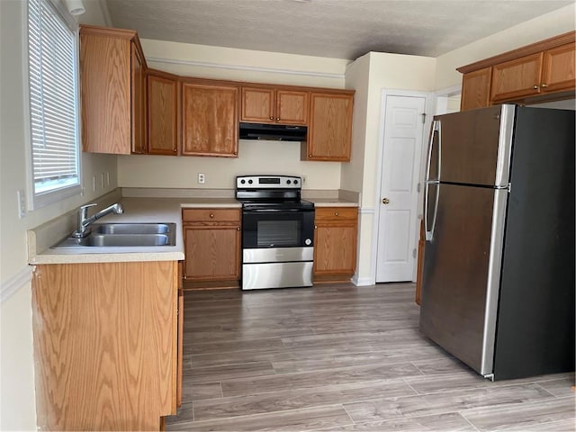 kitchen featuring a textured ceiling, light wood-type flooring, stainless steel appliances, and sink