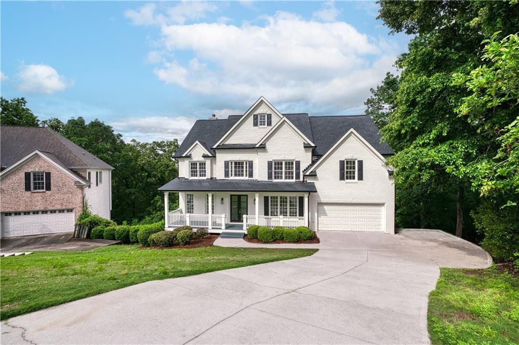 view of front of home featuring covered porch, a garage, and a front lawn