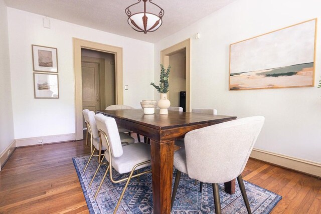 dining area with wood-type flooring and baseboards