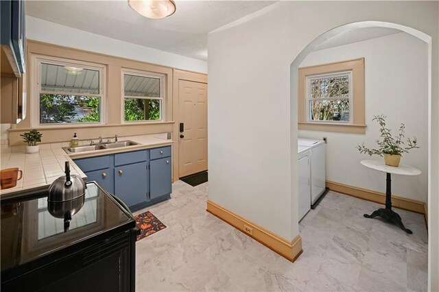 kitchen with a sink, blue cabinetry, black / electric stove, and tile countertops