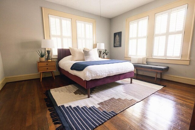 bedroom with a ceiling fan, wood finished floors, visible vents, and baseboards