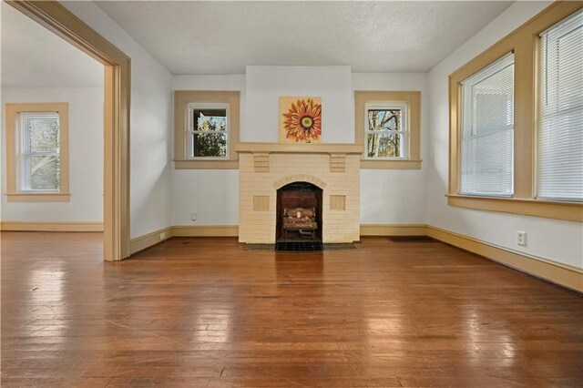 unfurnished dining area featuring wood-type flooring, visible vents, a fireplace, and baseboards