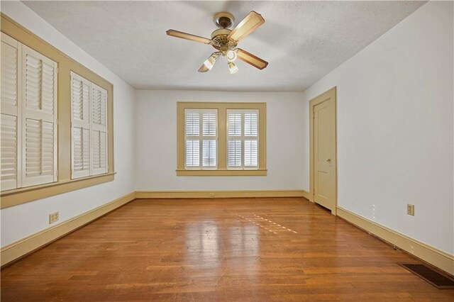 unfurnished room featuring baseboards, visible vents, and wood finished floors