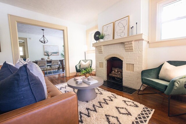 sitting room with a brick fireplace, plenty of natural light, and wood finished floors