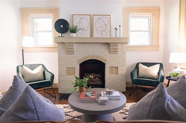 living room featuring a brick fireplace and wood finished floors