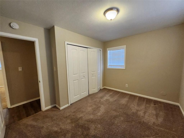 unfurnished bedroom featuring a textured ceiling, a closet, and dark colored carpet