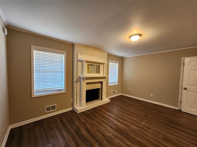 unfurnished living room featuring a fireplace, ornamental molding, and dark hardwood / wood-style floors