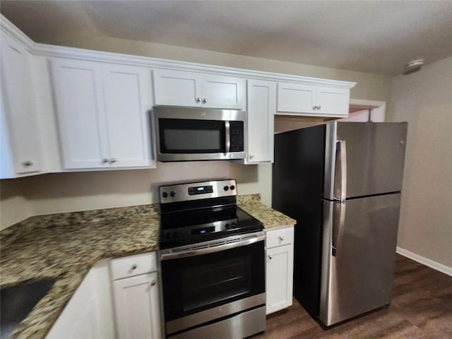 kitchen featuring stainless steel appliances, sink, white cabinetry, dark stone counters, and dark hardwood / wood-style floors