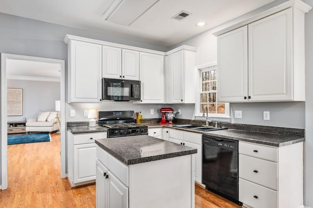 kitchen featuring white cabinets, a sink, light wood-style flooring, and black appliances