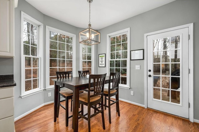 dining area with baseboards, a notable chandelier, a wealth of natural light, and light wood-style floors