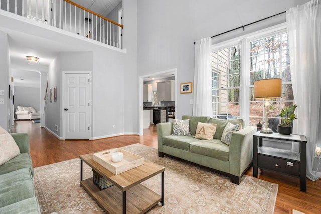 living room featuring a towering ceiling, baseboards, and wood finished floors