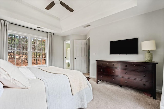 bedroom with a tray ceiling, light colored carpet, visible vents, ceiling fan, and baseboards