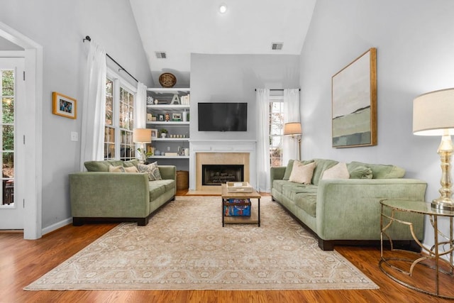 living area with visible vents, vaulted ceiling, and wood finished floors