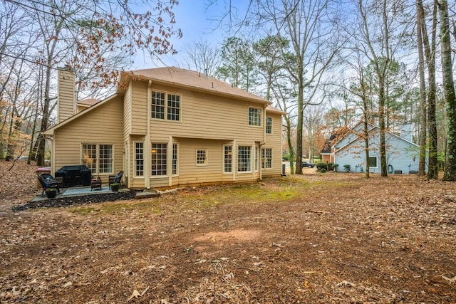 rear view of property featuring a patio area and a chimney