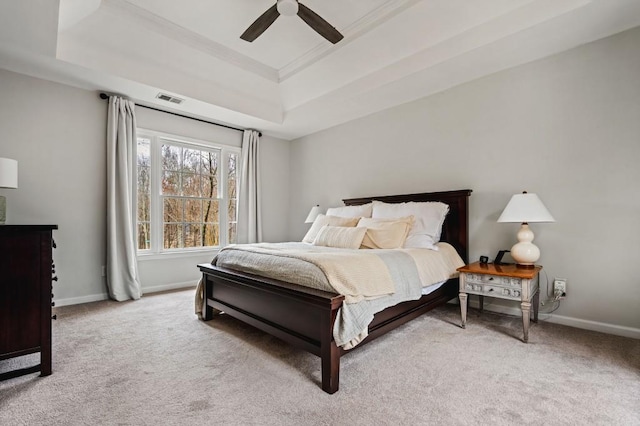 bedroom with a tray ceiling, baseboards, visible vents, and carpet