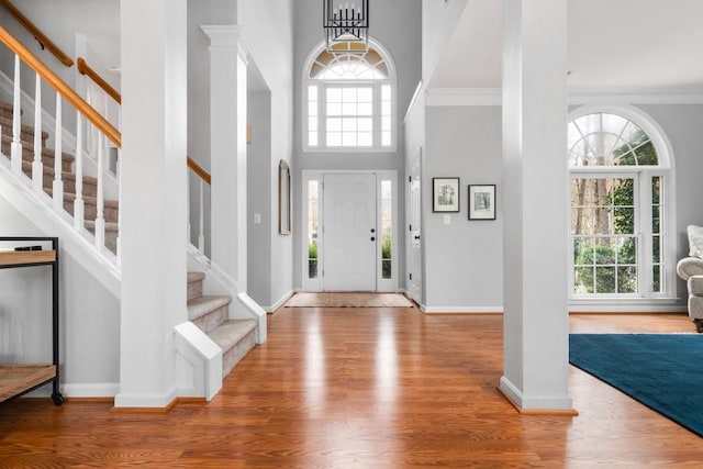 entrance foyer featuring stairs, wood finished floors, a towering ceiling, and crown molding