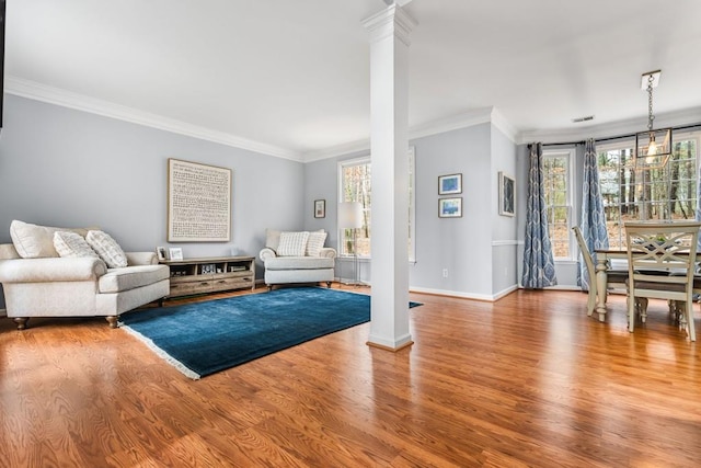 living area featuring ornate columns, ornamental molding, and wood finished floors