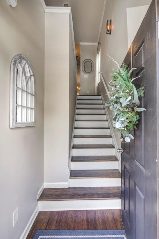 stairs with wood-type flooring and crown molding