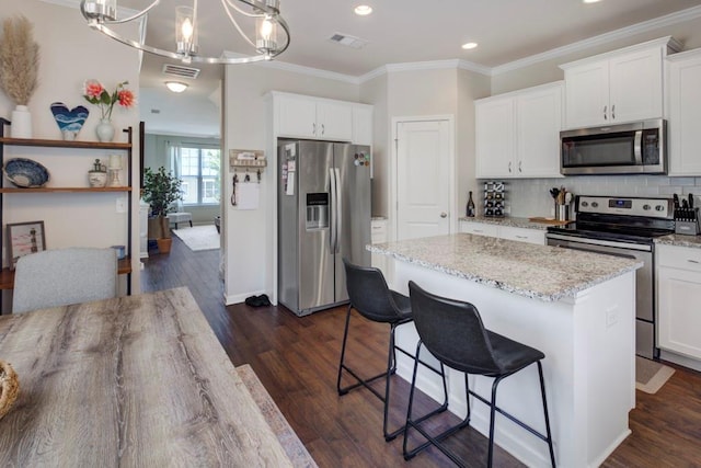 kitchen featuring a kitchen island, dark wood-type flooring, stainless steel appliances, and white cabinetry