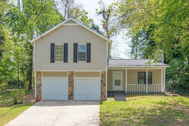 split level home featuring a front lawn, stone siding, a garage, covered porch, and driveway