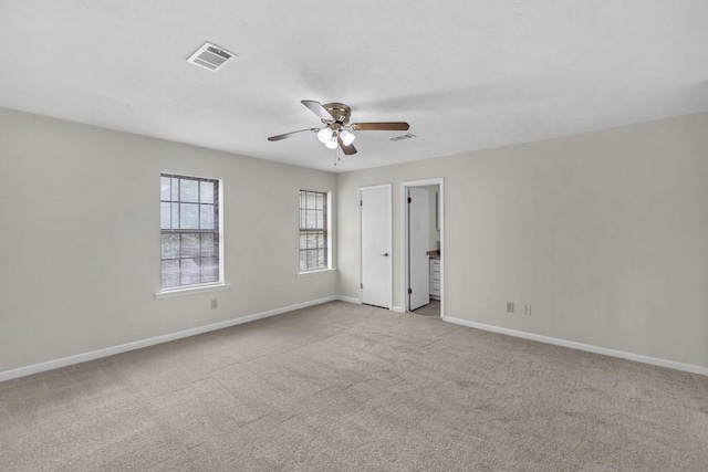 carpeted empty room with visible vents, a ceiling fan, and baseboards
