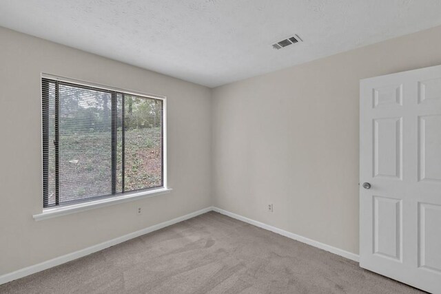 carpeted empty room featuring baseboards and visible vents