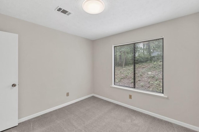 spare room with visible vents, baseboards, and light carpet