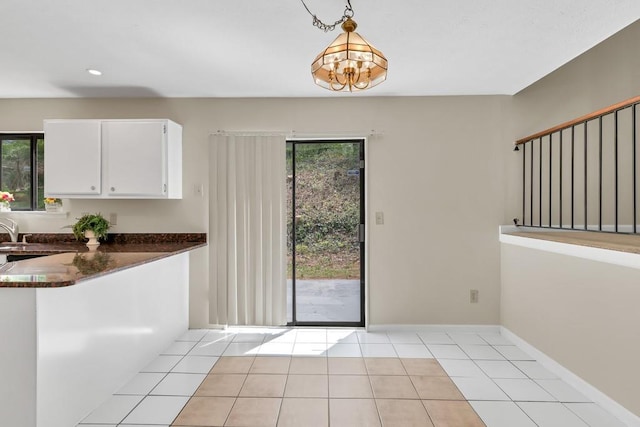 interior space featuring baseboards, a chandelier, plenty of natural light, and light tile patterned floors