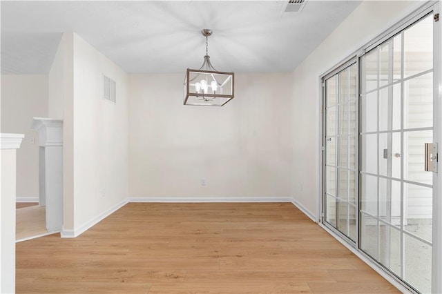 unfurnished dining area with light wood finished floors, baseboards, visible vents, and an inviting chandelier