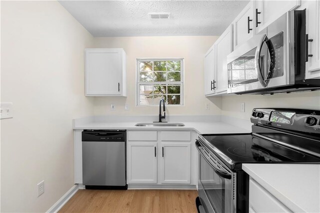 kitchen with light countertops, light wood-type flooring, appliances with stainless steel finishes, and a sink