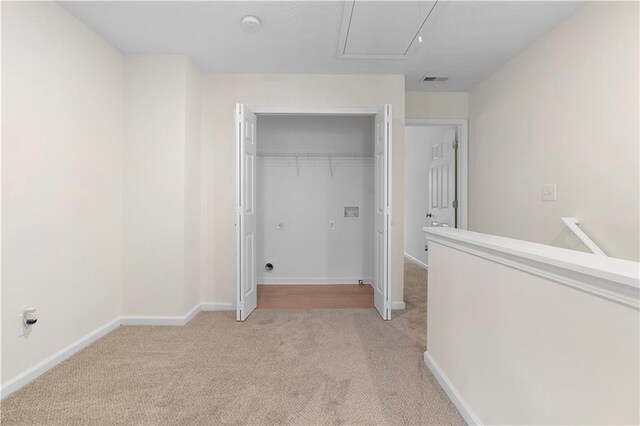 unfurnished bedroom with attic access, baseboards, a closet, and light colored carpet