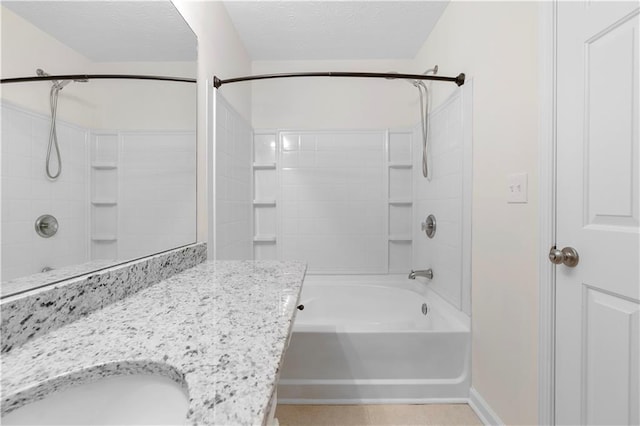 bathroom with baseboards, a sink,  shower combination, and a textured ceiling
