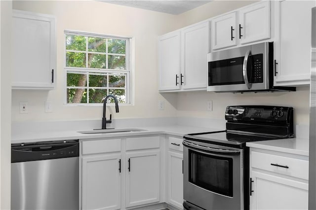 kitchen with appliances with stainless steel finishes, white cabinetry, and a sink