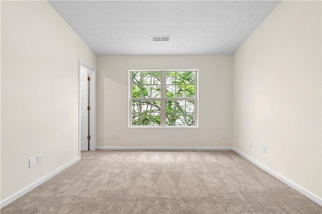 carpeted spare room featuring a textured ceiling, baseboards, and visible vents