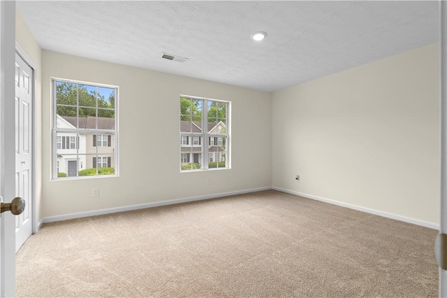 unfurnished room with baseboards, light carpet, visible vents, and a wealth of natural light