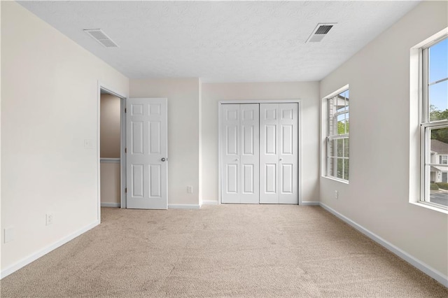 unfurnished bedroom with carpet floors, multiple windows, visible vents, and baseboards