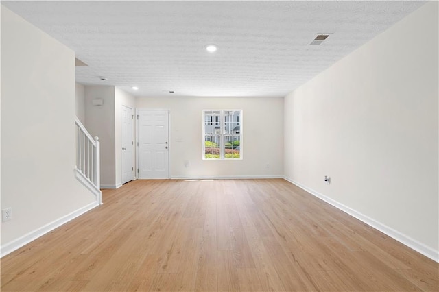 unfurnished living room with stairs, light wood-type flooring, baseboards, visible vents, and recessed lighting